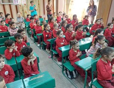Ägyptische Kindergartenkinder sitzen an grünen Pulten im Unterricht. Dazwischen stehen ein paar ältere Frauen aus Österreich. 