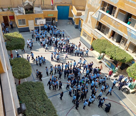Blick von oben in den Schulinnenhof einer ägyptischen Schule. Die Schüler*innen haben Pause und sind im Hof versammelt.