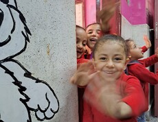 Ägyptische Kinder schauen aus der Tür zu ihrem Klassenzimmer und winken fröhlich in die Kamera.
