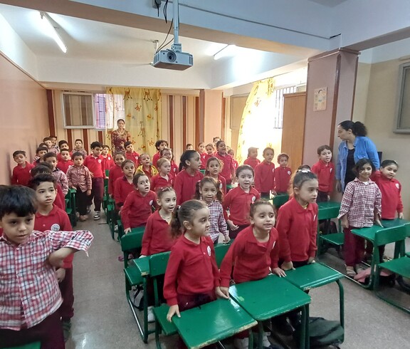 Blick in ein Klassenzimmer des Kindergartens in Ägypten. Die Kinder tragen rote Pullover und sitzen an grünen Pulten.