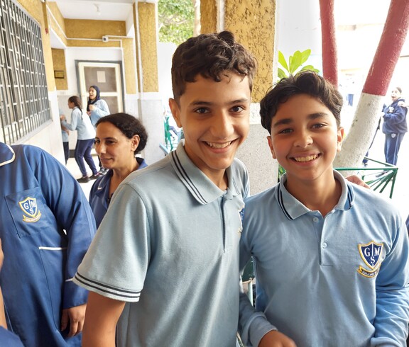 Zwei ägyptische Schüler in blauer Schuluniform lächeln in die Kamera.